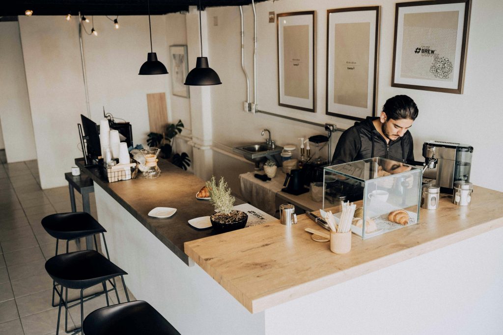 A barista works in a modern café with minimalistic décor and warm lighting.