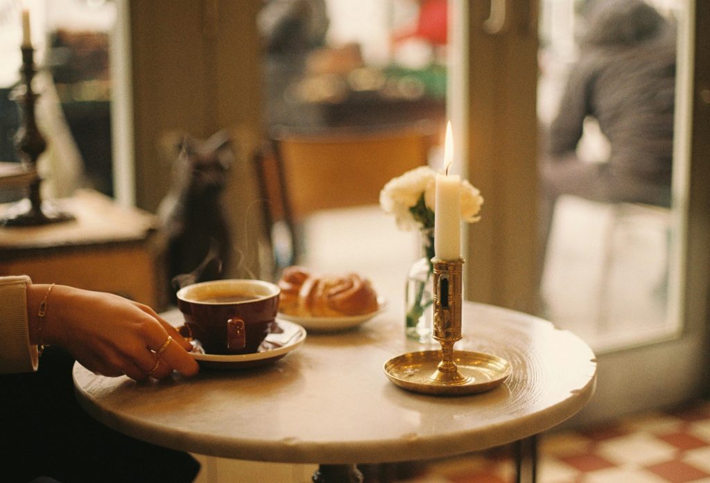 Warm café setting in London with coffee, pastries, and candlelight ambiance.