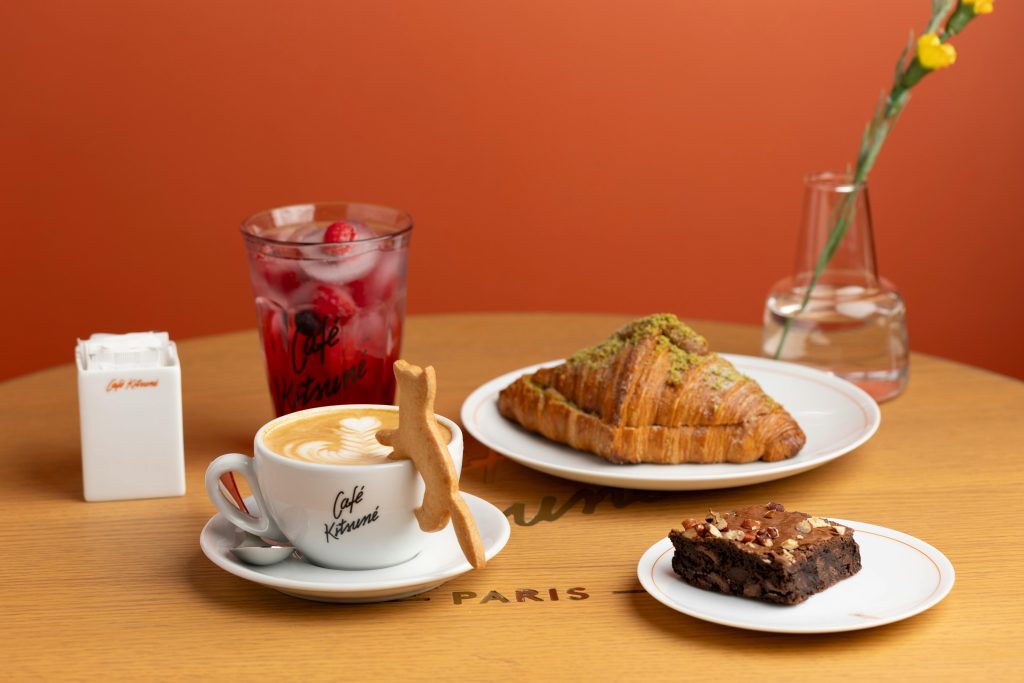 Elegant cafe setting with a cappuccino, croissant, brownie, and iced drink, perfect for a Parisian brunch vibe.
