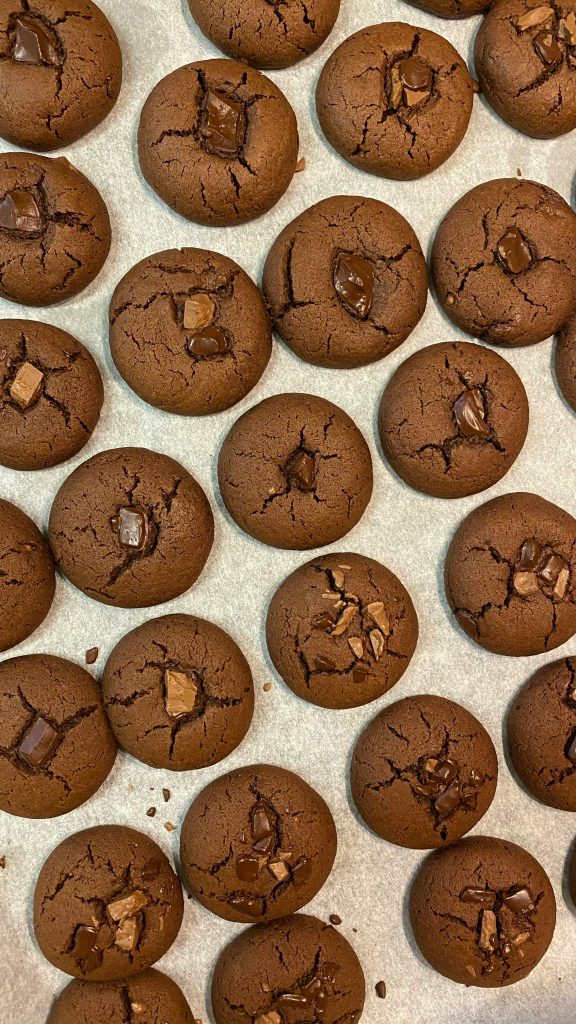 Delicious freshly baked chocolate cookies arranged on a white surface, perfect for dessert lovers.